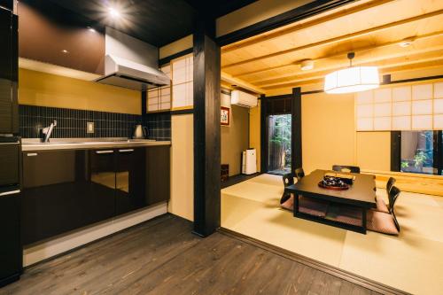 a living room with a table and a kitchen at Miro Hachijo Genmachi Tei in Kyoto