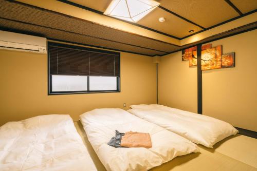 京都市にある美盧八条源町邸の窓付きの客室で、白いベッド2台が備わります。
