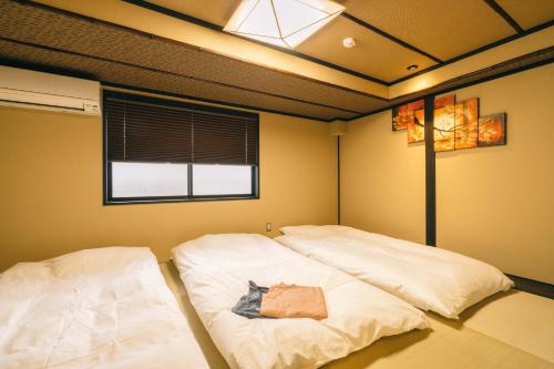two white beds in a room with a window at Miro Hachijo Genmachi Tei in Kyoto