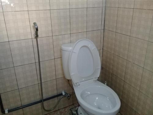 a bathroom with a toilet in a tiled wall at Cinnamon Guest House in Bajawa