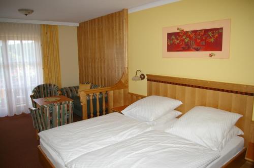 a bedroom with a white bed and a dining room at Pension Zur Alten Schmiede in Zwiesel