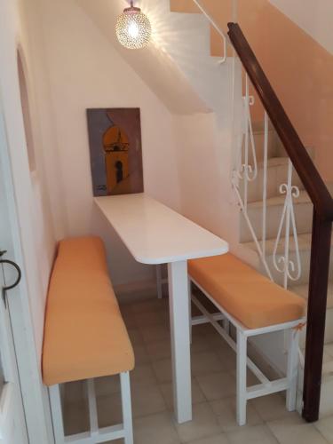 a table and benches in a small room with a staircase at Dar es Salam-Alta in Asilah