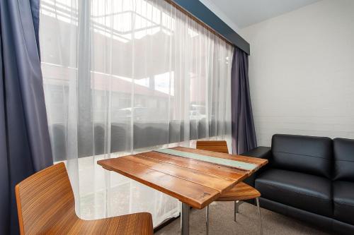 een kamer met een tafel, een bank en een raam bij Winsor Park Motor Inn in Albury