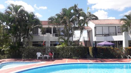 une personne assise devant une maison avec piscine dans l'établissement Casa Quinta Melgar, à Melgar