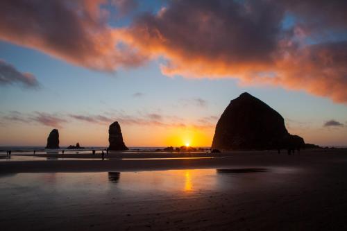 a sunset on a beach with two large rocks at Inn at Cannon Beach in Cannon Beach