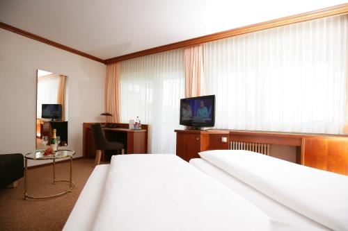 a hotel room with a bed and a television at Badhotel Restaurant Stauferland in Bad Boll