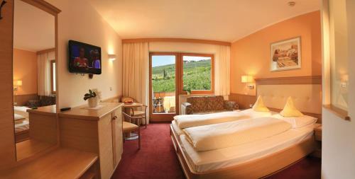 a hotel room with a large bed and a window at Hotel Eichenhof in Tirolo