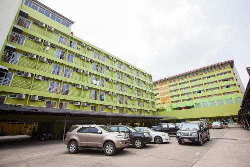 a parking lot with cars parked in front of a building at The Aiyapura Bangkok in Bangkok