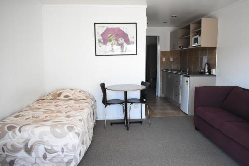 a room with a bed and a table and a couch at Devonwood Motel in Rotorua
