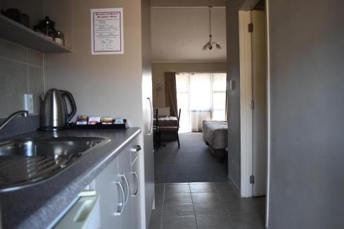 a kitchen with a sink and a room with a bed at Devonwood Motel in Rotorua