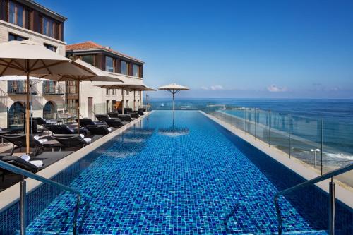 a swimming pool with chairs and umbrellas and the ocean at The Setai Tel Aviv, a Member of the leading hotels of the world in Tel Aviv