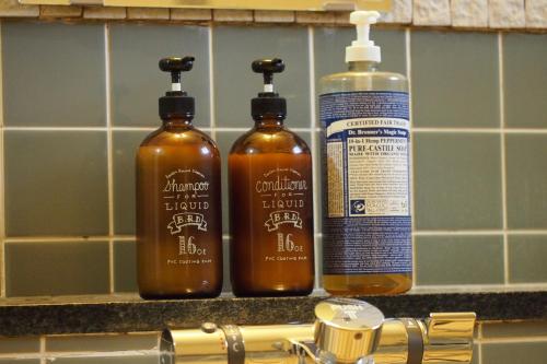 three bottles of soap on a counter next to a sink at Okushiga Lodge Yama no Manimani in Yamanouchi