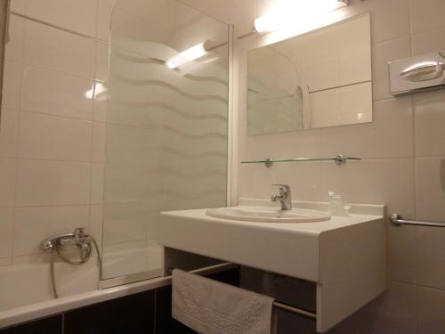 uma casa de banho com um lavatório, um espelho e um chuveiro em Hôtel du Sud Vieux Port em Marselha