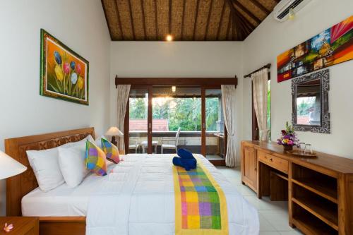 a bedroom with a bed with a desk and a window at Wenara Bali Bungalows in Ubud