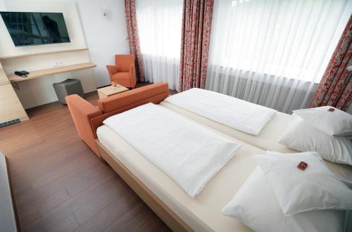 a hotel room with a bed and a chair at Badhotel Restaurant Stauferland in Bad Boll