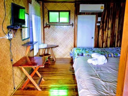 a bedroom with a bed and a television and a table at Bansuanphuhong Resort in Chiang Khan