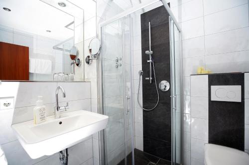 a white bathroom with a sink and a shower at Badhotel Restaurant Stauferland in Bad Boll