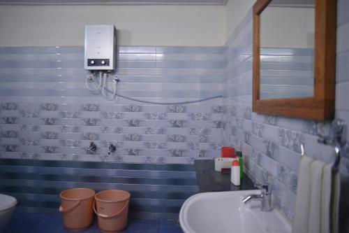 Un baño con lavabo, inodoro y espejo. en Agasthya Homestay - With Kitchenette, en Madikeri