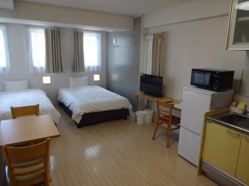 Habitación de hotel con 2 camas y TV en Across Omoromachi Naha en Naha