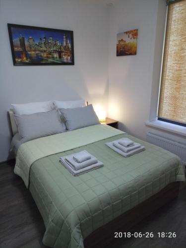 エカテリンブルクにあるApartament MEGAPOLIS & RADIUSのベッドルーム1室(緑のベッド1台、タオル2枚付)