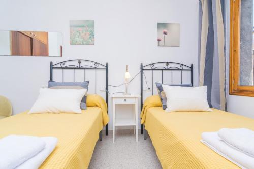 two beds in a room with yellow sheets at Ca Na Dora in Santanyi
