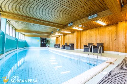 a large swimming pool with chairs in a building at Hotel Sorsanpesä in Seinäjoki