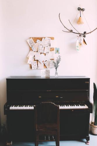 a black piano against a white wall with notes on the wall at ÉTÉ Dalat in Da Lat