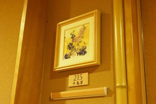 a painting of flowers on a wall with a sign at Hot spring inn Snow country(yukiguni) in Tsunan