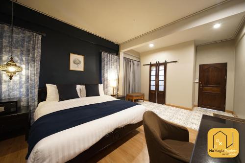 a bedroom with a large bed and a chair at Na Vayla PaPlern in Bangkok
