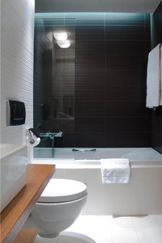 a bathroom with a white toilet and a bath tub at Capsis Hotel Thessaloniki in Thessaloniki