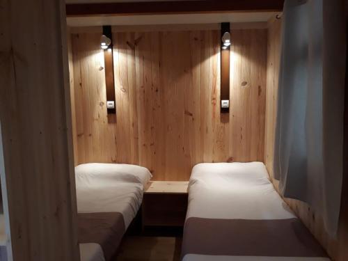two beds in a room with wooden walls and lights at La Masia in Sant Pere Pescador