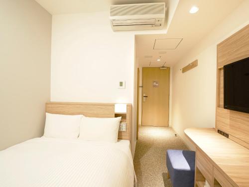 a hotel room with a bed and a tv at Sotetsu Fresa Inn Tokyo Kinshicho in Tokyo