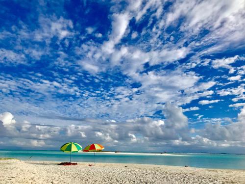 two umbrellas sitting on a beach with the ocean at Mathiveri Thundi Inn in Mathiveri