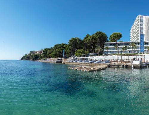 a body of water with a pier and a building at Meliá Calviá Beach in Magaluf