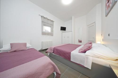 two beds in a room with white walls and purple sheets at Apartmani Rudi in Vir