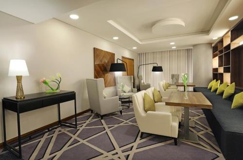 a lobby with a waiting room with chairs and a table at Millennium Madinah Airport in Al Madinah