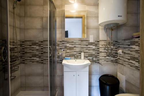 a bathroom with a sink and a glass shower at Apartamenty Piaskowe Rowy in Rowy