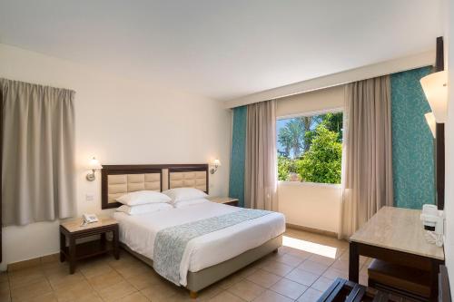 a hotel room with a bed and a window at Avanti Holiday Village in Paphos City