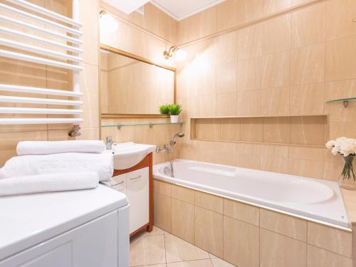 a bathroom with a tub and a sink at VacationClub - Bryza 7 Apartament 5 in Świnoujście