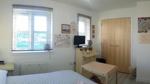 a bedroom with a bed and a desk and a television at BroomHouse HomeStay in Edinburgh