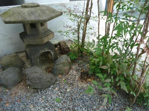 a stone bird bath in a garden with plants at Nagoya Motoyama House C in Nagoya