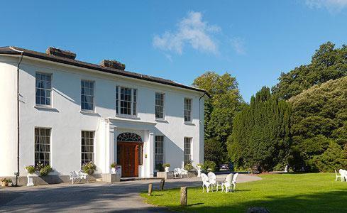 una casa blanca con sillas blancas delante en Springfort Hall Hotel, en Mallow