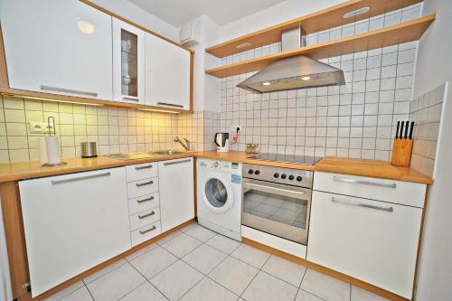 cocina con armarios blancos, lavadora y secadora en Grand Apartments Tulipan, en Sopot