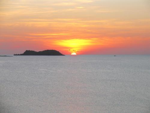 a sunset over the ocean with an island in the distance at Green Roof Inn in Carriacou