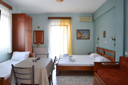 a room with two beds and a table and chairs at Vergina in Skala Potamias