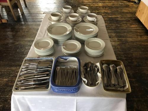 a table with plates and cups and utensils on it at Hotel Repvåg in Repvåg