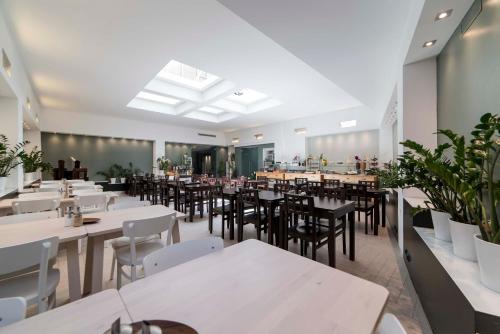 a restaurant with white tables and chairs and plants at Hotel Montestella in Salerno