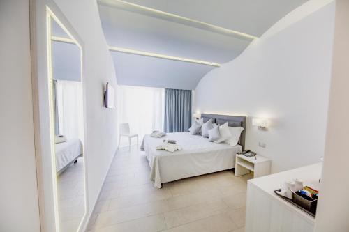 a white bedroom with a bed and a table at Ossuna Bay Hotel Boutique in Cefalù