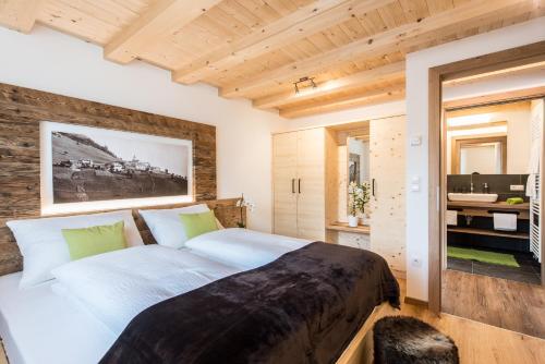 a bedroom with a large bed and a bathroom at Tallnerhof in Schenna