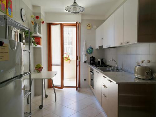 a kitchen with white cabinets and a table in it at Cagliari Family Apartment in Cagliari